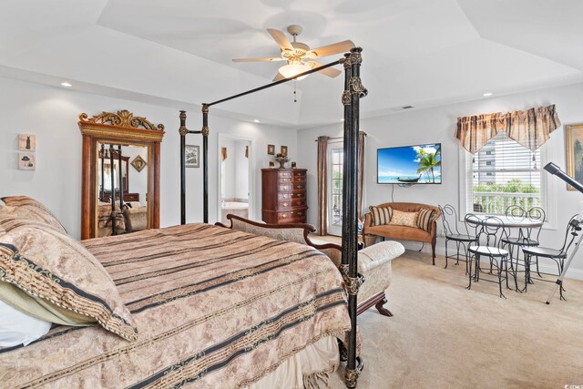 bedroom with ceiling fan, light colored carpet, and a tray ceiling