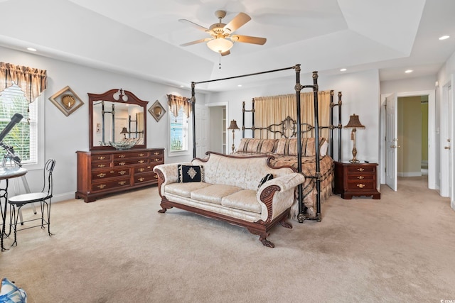 bedroom featuring recessed lighting, a tray ceiling, light colored carpet, and baseboards