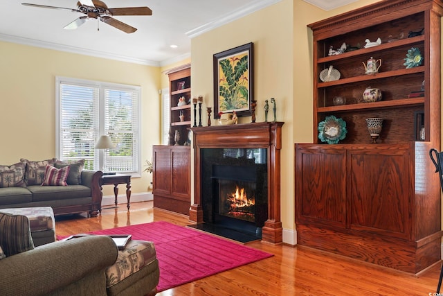 living room with ceiling fan, ornamental molding, and light hardwood / wood-style floors