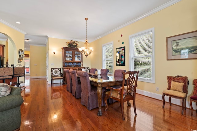 dining space with ornamental molding, hardwood / wood-style flooring, and a notable chandelier