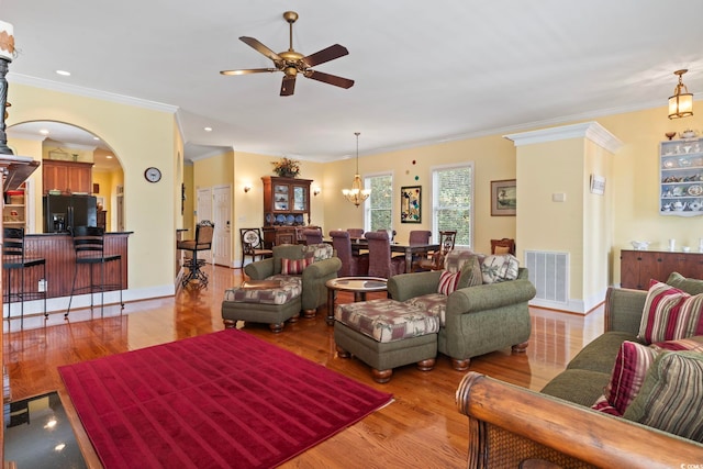 living room featuring ornamental molding, ceiling fan with notable chandelier, and light hardwood / wood-style flooring