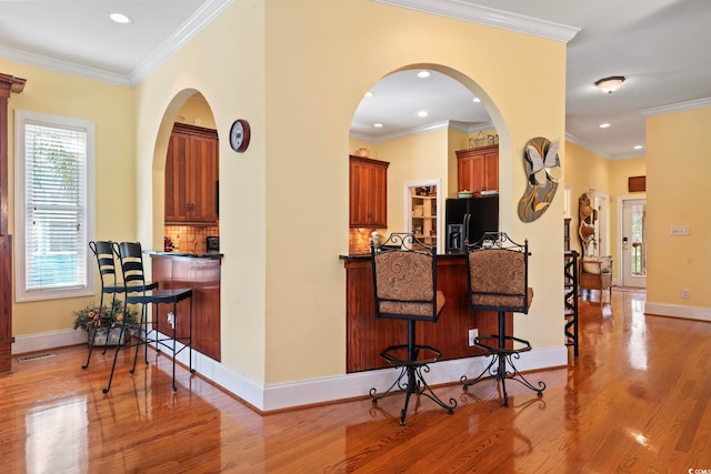 kitchen featuring black fridge, ornamental molding, decorative backsplash, and light hardwood / wood-style floors