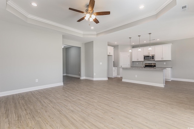 unfurnished living room with ornamental molding and a tray ceiling