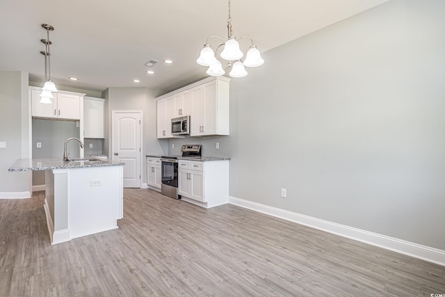 kitchen featuring a kitchen island with sink, pendant lighting, white cabinets, and stainless steel appliances