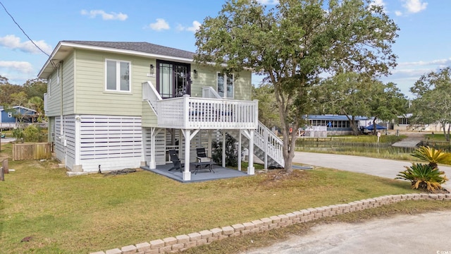 coastal home with a front yard, a deck, and a patio area