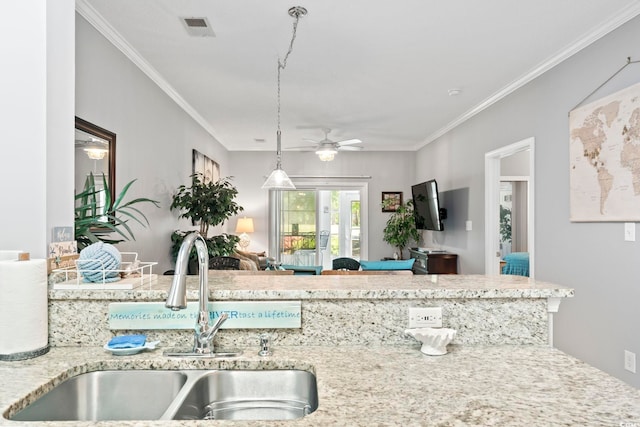 kitchen featuring hanging light fixtures, ceiling fan, light stone countertops, crown molding, and sink