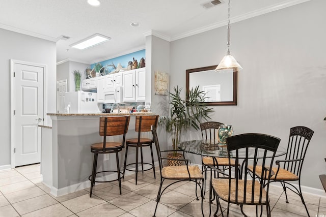 kitchen with kitchen peninsula, white cabinets, crown molding, decorative light fixtures, and white appliances