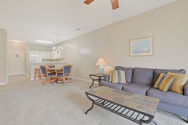 carpeted living room with ceiling fan with notable chandelier