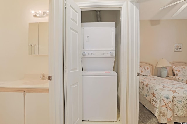 laundry area featuring stacked washer and dryer, ceiling fan, and sink