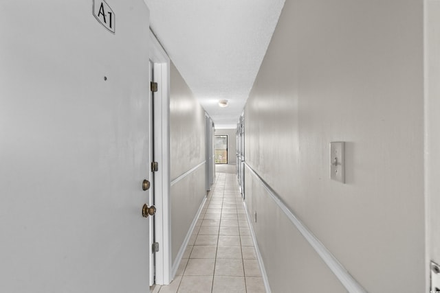 corridor featuring light tile patterned flooring and a textured ceiling