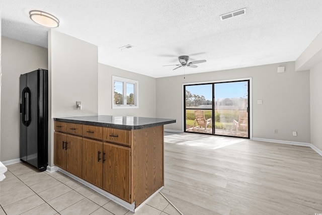 kitchen with light hardwood / wood-style floors, black fridge, ceiling fan, and a healthy amount of sunlight