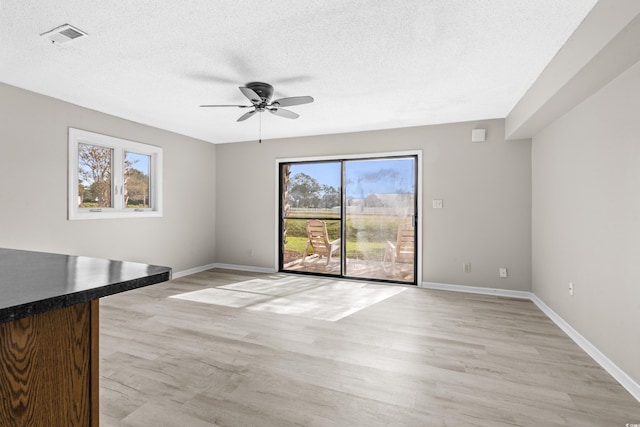 unfurnished living room featuring ceiling fan, light hardwood / wood-style floors, and a textured ceiling