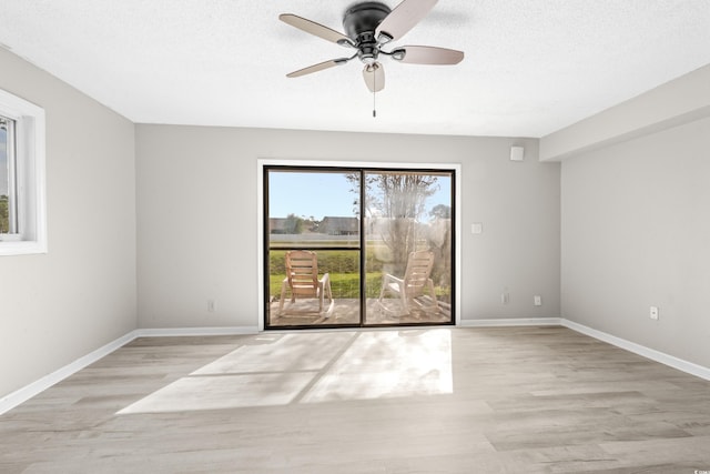 spare room with ceiling fan, light hardwood / wood-style floors, and a textured ceiling