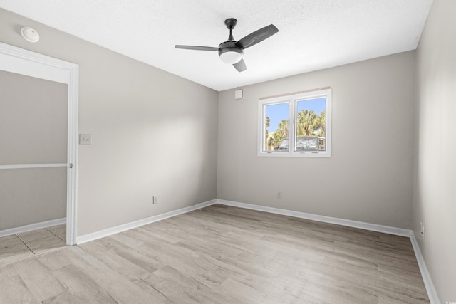 empty room with ceiling fan, light wood-type flooring, and a textured ceiling