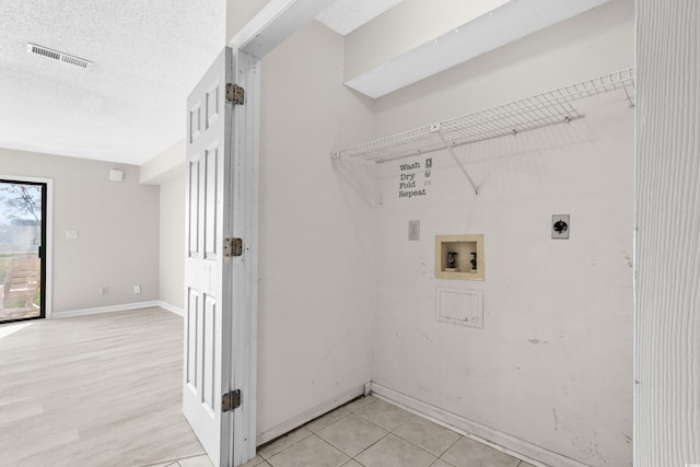 washroom featuring washer hookup, a textured ceiling, light hardwood / wood-style flooring, and electric dryer hookup