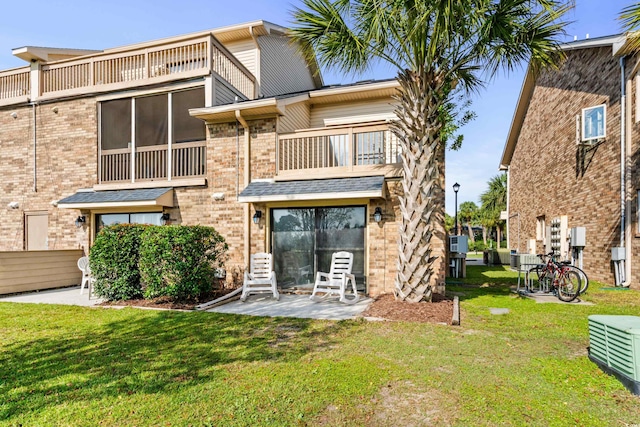 back of property with a yard, a patio area, and a balcony