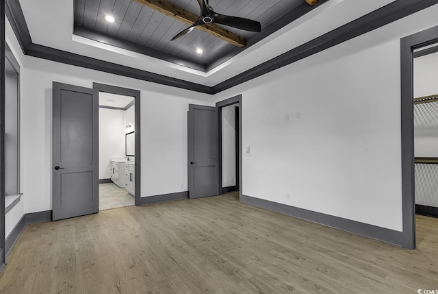 unfurnished bedroom with a raised ceiling, ensuite bath, and light hardwood / wood-style floors