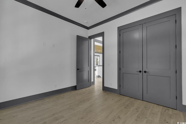 unfurnished bedroom with ceiling fan, light hardwood / wood-style floors, crown molding, and a closet