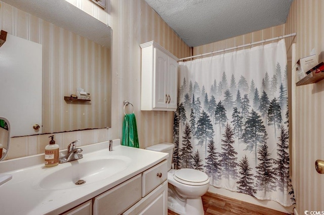 bathroom featuring a textured ceiling, hardwood / wood-style flooring, vanity, and toilet