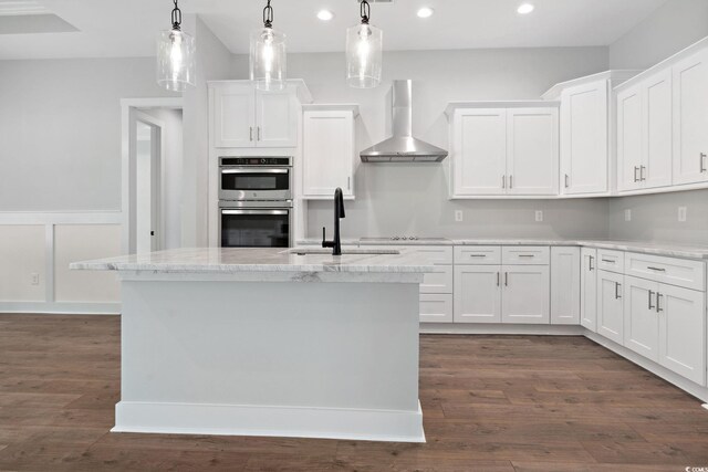 297 Waterfall Cir, Little River, SC 29566 - kitchen featuring wall chimney range hood, recessed lighting, white cabinets, stainless steel double oven, and an island with sink