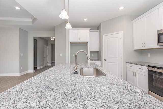 kitchen featuring sink, appliances with stainless steel finishes, pendant lighting, light stone countertops, and white cabinets