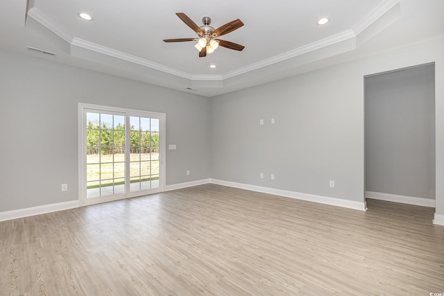 unfurnished room with light wood-type flooring, baseboards, visible vents, and a tray ceiling