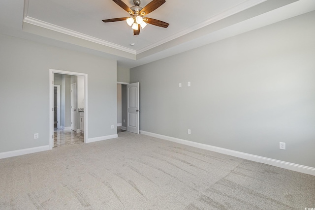 unfurnished bedroom featuring ensuite bathroom, ornamental molding, light colored carpet, ceiling fan, and a raised ceiling