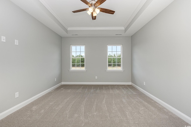 unfurnished room with a raised ceiling, crown molding, carpet floors, and ceiling fan