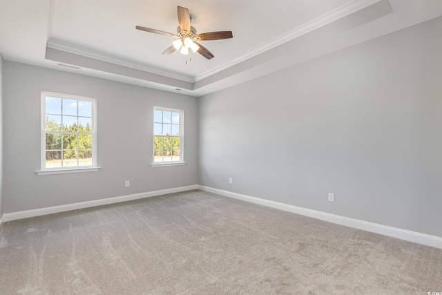 carpeted spare room featuring crown molding, a raised ceiling, visible vents, ceiling fan, and baseboards