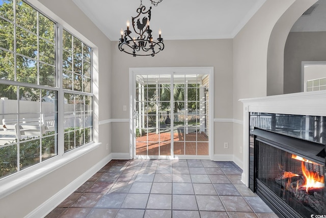 tiled dining area featuring plenty of natural light, ornamental molding, and an inviting chandelier