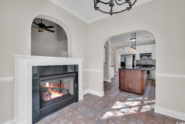 kitchen with ornamental molding, stainless steel appliances, backsplash, white cabinets, and a fireplace