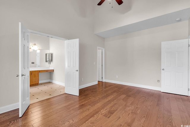 unfurnished bedroom featuring ceiling fan, ensuite bathroom, light wood-type flooring, and built in desk