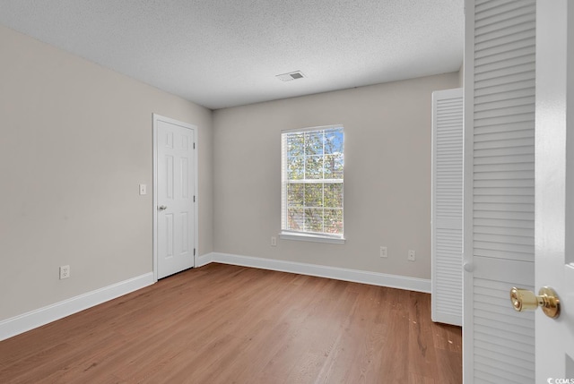 unfurnished bedroom featuring wood-type flooring, a closet, and a textured ceiling