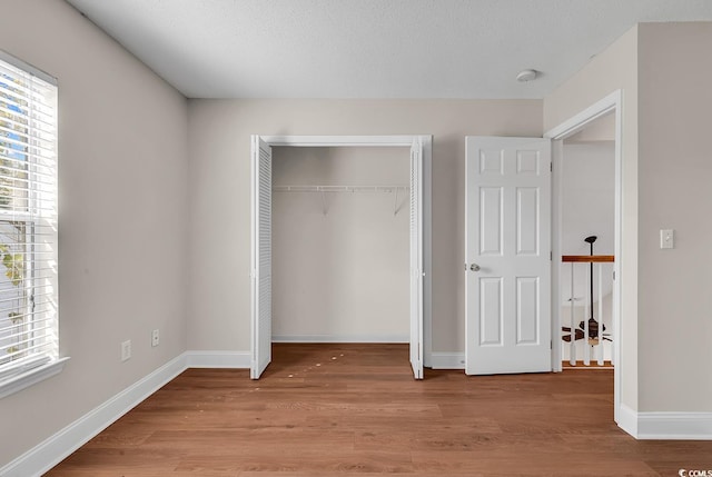 unfurnished bedroom featuring a textured ceiling, a closet, and light hardwood / wood-style floors