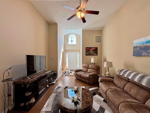 living room with a textured ceiling, hardwood / wood-style flooring, high vaulted ceiling, and ceiling fan