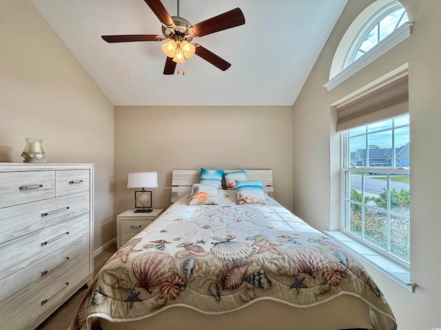 bedroom with vaulted ceiling, multiple windows, and ceiling fan