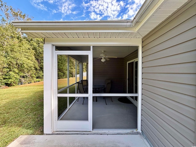 entrance to property featuring a lawn and ceiling fan