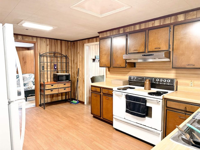 kitchen with under cabinet range hood, white appliances, light wood finished floors, and light countertops