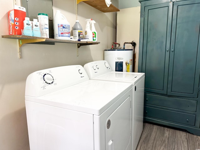 laundry room with water heater, washing machine and dryer, cabinet space, and wood finished floors