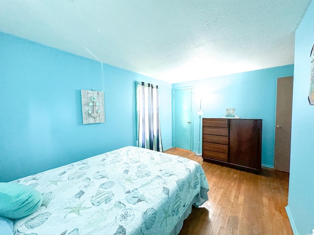 bedroom with a closet, a textured ceiling, and wood finished floors