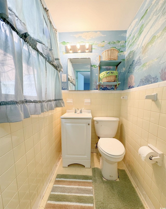 bathroom with toilet, tile walls, wainscoting, wallpapered walls, and vanity