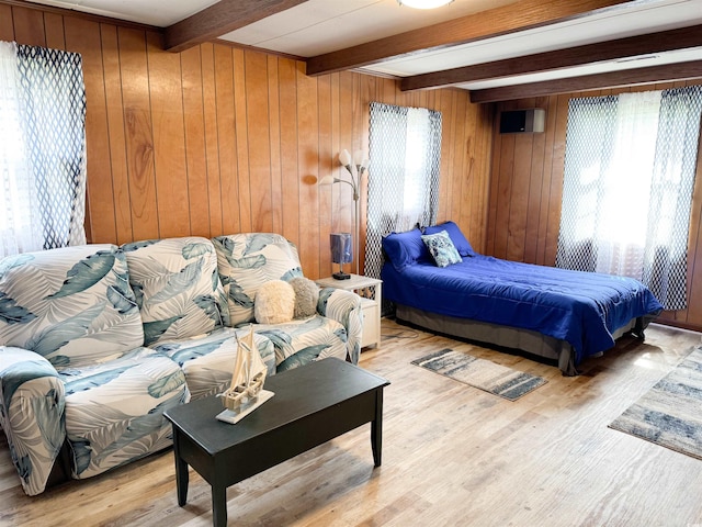 bedroom with beamed ceiling, wooden walls, and wood finished floors