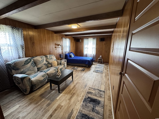 bedroom featuring beam ceiling, light wood-style flooring, and wood walls