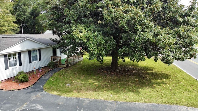 view of side of property featuring a lawn and a shingled roof