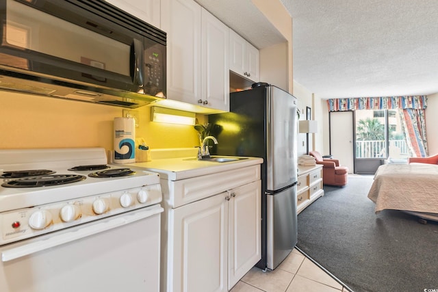 kitchen featuring stainless steel refrigerator, white range oven, white cabinetry, and sink