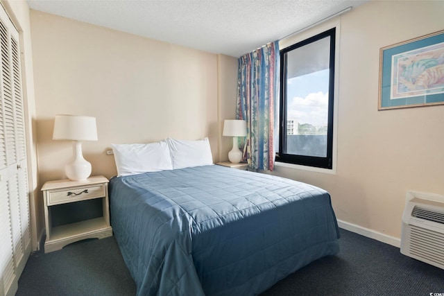 carpeted bedroom featuring a textured ceiling, a closet, and an AC wall unit