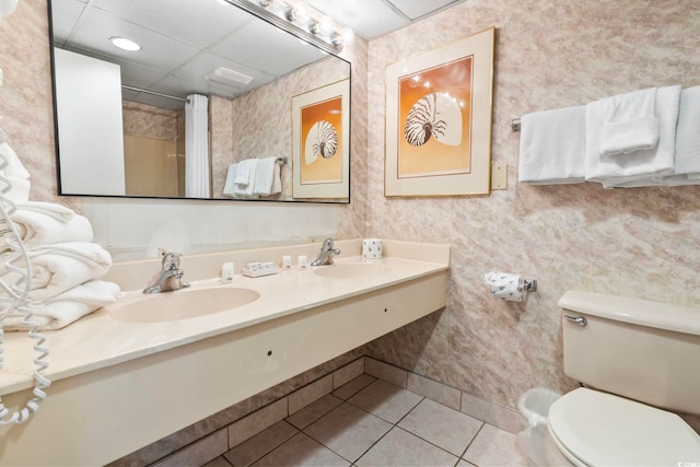 bathroom featuring vanity, a drop ceiling, tile patterned floors, walk in shower, and toilet