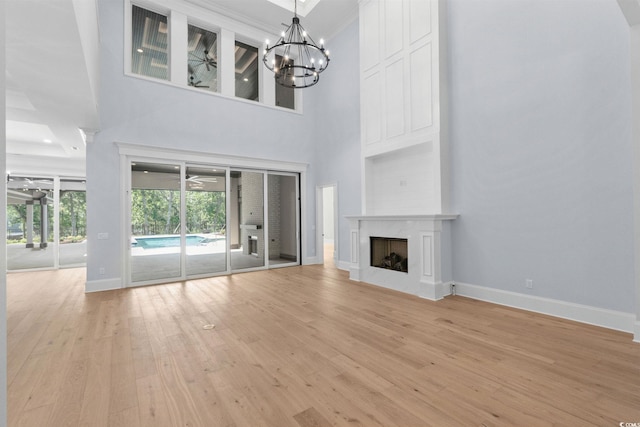372 Chamberlin Rd, Myrtle Beach, SC 29588 - unfurnished living room featuring light wood-type flooring, a premium fireplace, a high ceiling, a chandelier, and a ceiling fan