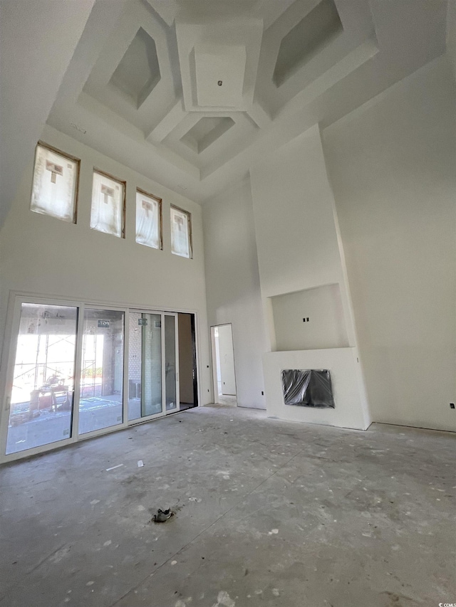 unfurnished living room with a fireplace and a towering ceiling