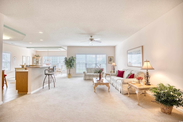 living room with light carpet, a textured ceiling, healthy amount of natural light, a ceiling fan, and recessed lighting